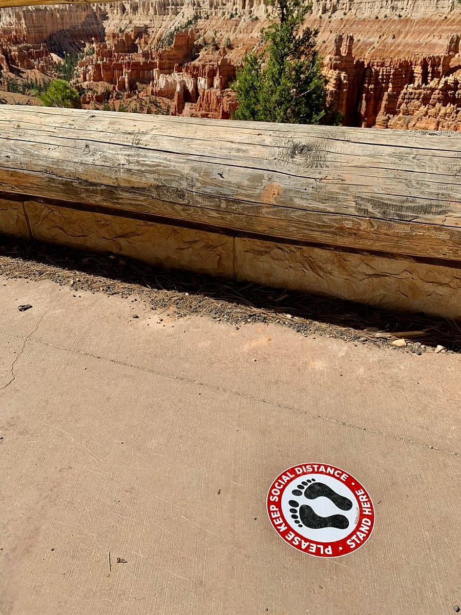 Reminders to stand socially distant at a Bryce Canyon Rim viewpoint contribute to a safe road trip