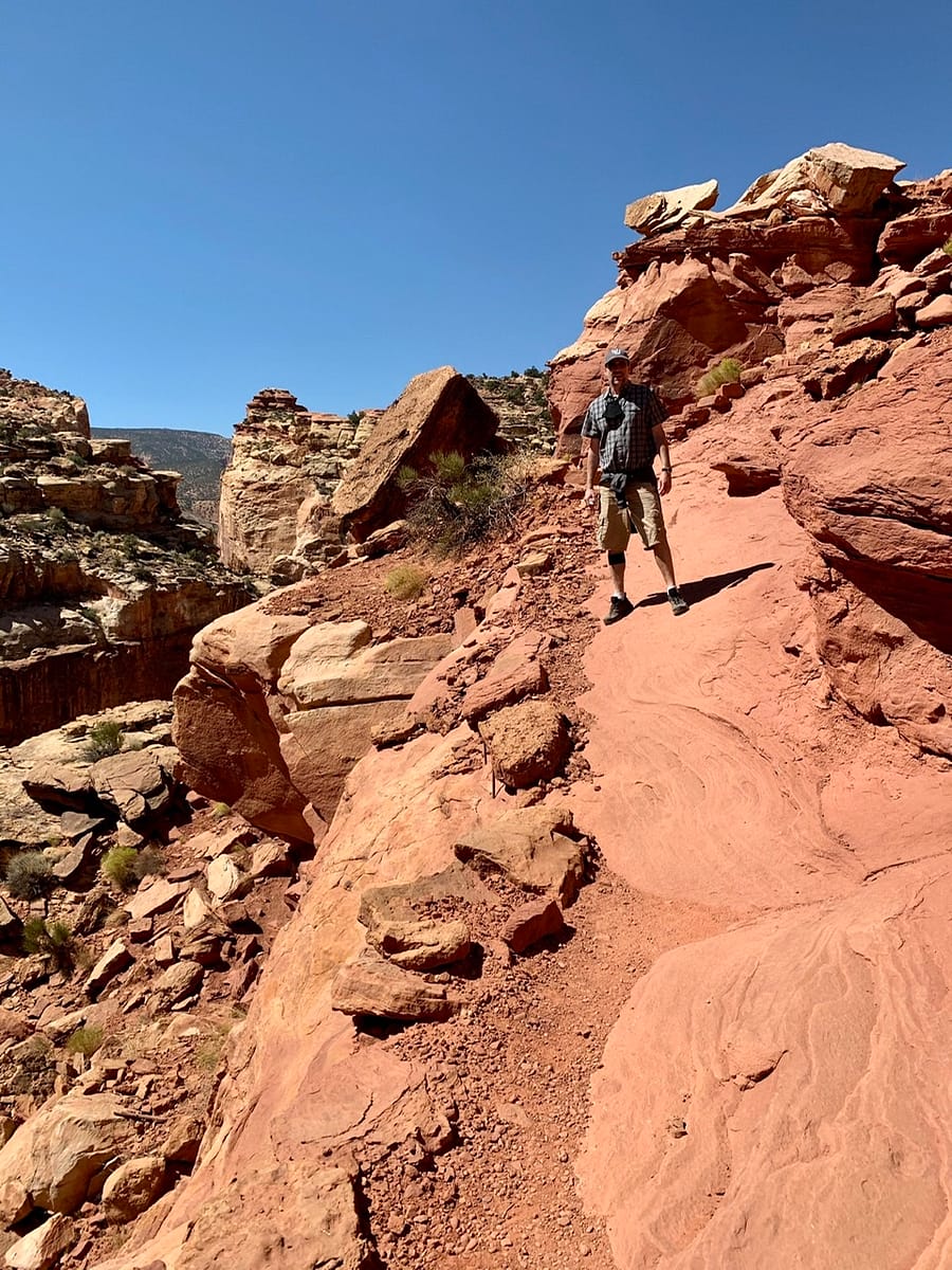 Standing on the steep sandstone trail while hiking to Cassidy Arch