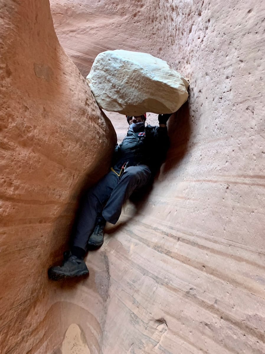 Sliding under a rock while canyoneering through a Utah slot canyon