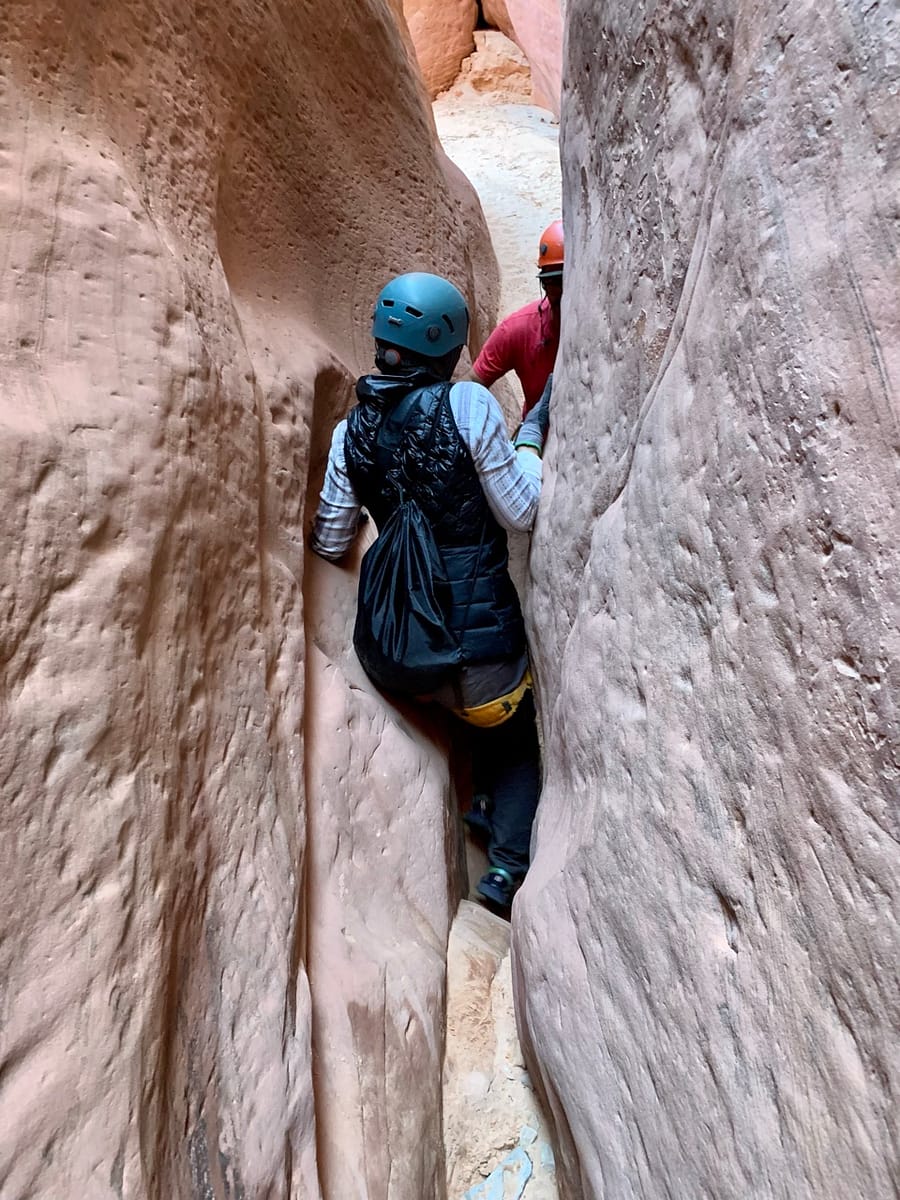 Squeezing through tight places while canyoneering through a Utah slot canyon