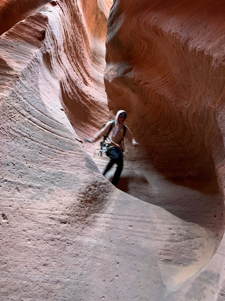 One of the East Zion Experience guides runs down a sandstone chute in Ladder Slot Canyon
