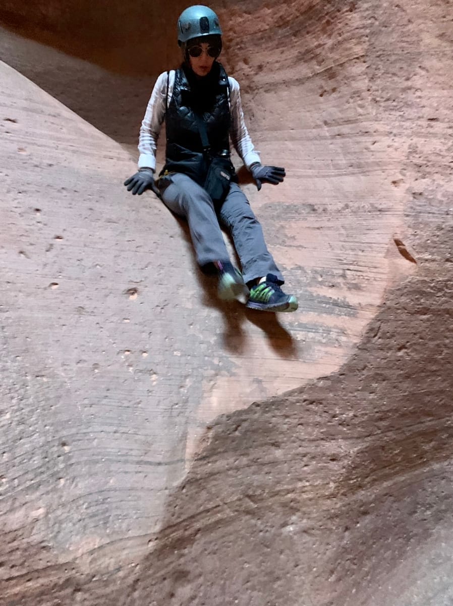 Sliding along the sandstone while canyoneering in a Utah slot canyon